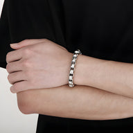 Bracelet pour homme en acier inoxydable argenté à maille vénitienne épaisse porté au poignet.