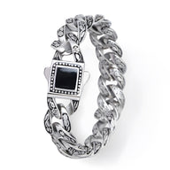 Bracelet homme en acier inoxydable argenté avec motif floral et pierre noire carrée centrale.