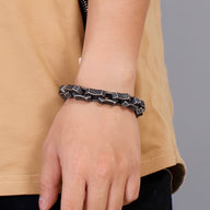 Bracelet en acier inoxydable noir avec motifs celtiques entrelacés porté au poignet homme.
