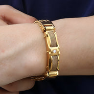 Bracelet en acier inoxydable doré avec strass central et maillons fins sur poignet masculin.