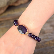 Bracelet femme perles améthyste violettes avec pierre facettée ovale sertie or.