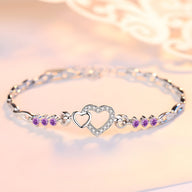 Bracelet en argent massif pour femme avec charme double cœur et petits cristaux violets.