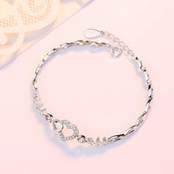Bracelet en argent massif avec charm double cœur serti de petits brillants, chaîne fine élégante.