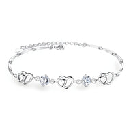 Bracelet fin en argent avec trois charms cœurs entrecoupés de deux pierres bleues scintillantes.