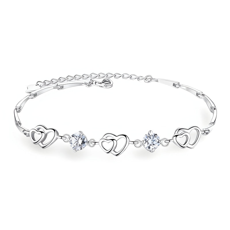 Bracelet fin en argent avec trois charms cœurs entrecoupés de deux pierres bleues scintillantes.