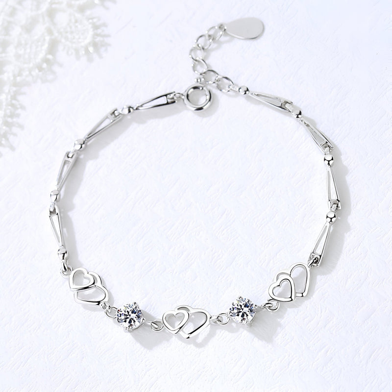 Bracelet en argent massif avec trois charms cœurs entrelacés et deux pierres scintillantes, modèle Milla.