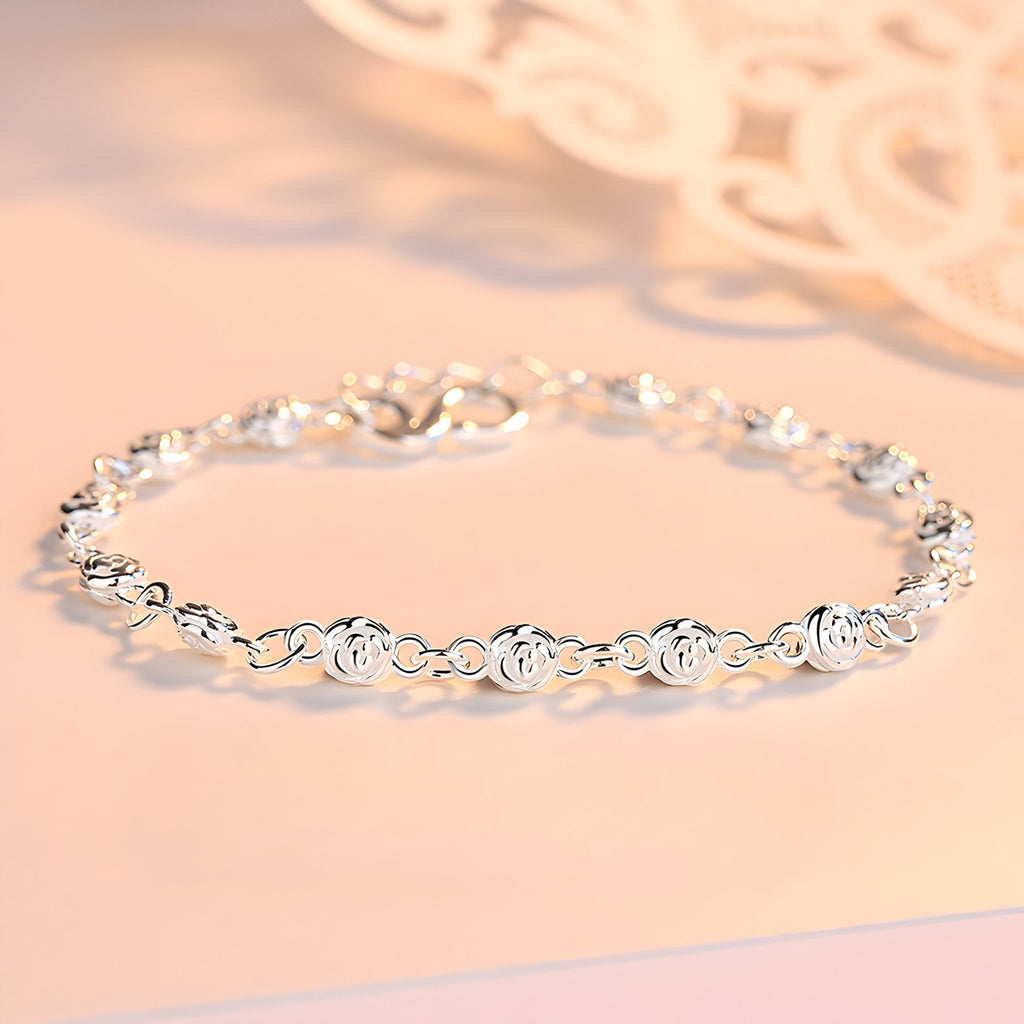 Bracelet en argent massif avec maillons ronds ornés de petits charms en forme de rose, modèle féminin élégant.