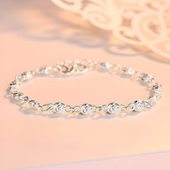 Bracelet en argent massif avec maillons ronds ornés de petits charms en forme de rose, modèle féminin élégant.