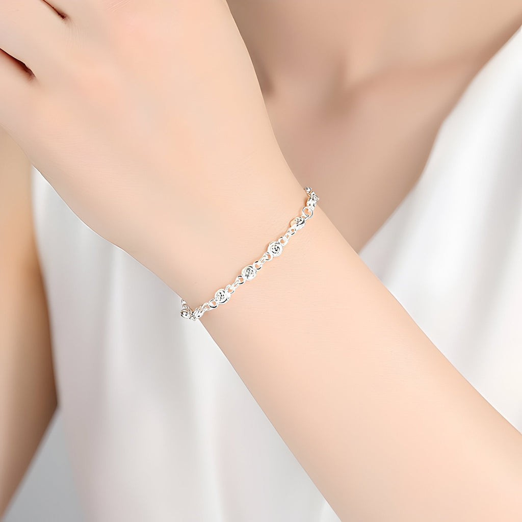 Bracelet en argent massif fin à maillons élégants porté sur poignet féminin avec chemise blanche.