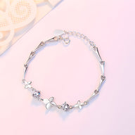 Bracelet en argent massif avec pendentifs trèfle à quatre feuilles et petites fleurs délicates.