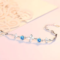 Bracelet en argent massif avec trèfles à quatre feuilles et pierres bleues scintillantes.