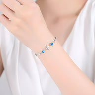 Bracelet argent massif pour femme avec trèfle à quatre feuilles et perles bleues.