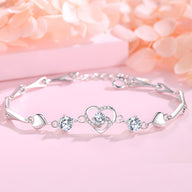 Bracelet en argent avec motif cœur ajouré et trois pierres scintillantes, style délicat pour femme.
