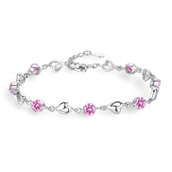 Bracelet en argent avec maillons cœur et pierres roses scintillantes.