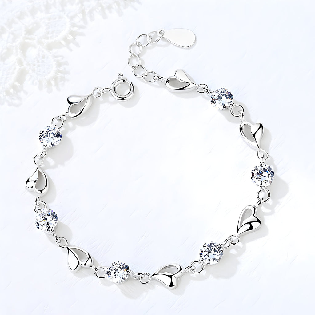 Bracelet en argent pur pour femme avec maillons en forme de cœur et pierres bleues brillantes.