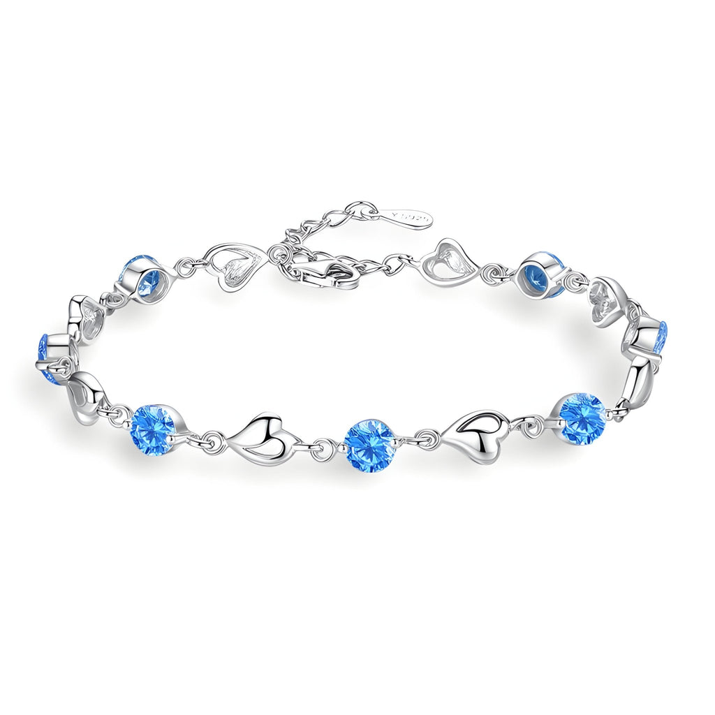 Bracelet en argent avec maillons en forme de cœur et pierres bleues scintillantes.