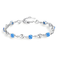 Bracelet en argent avec maillons en forme de cœur et pierres bleues scintillantes.