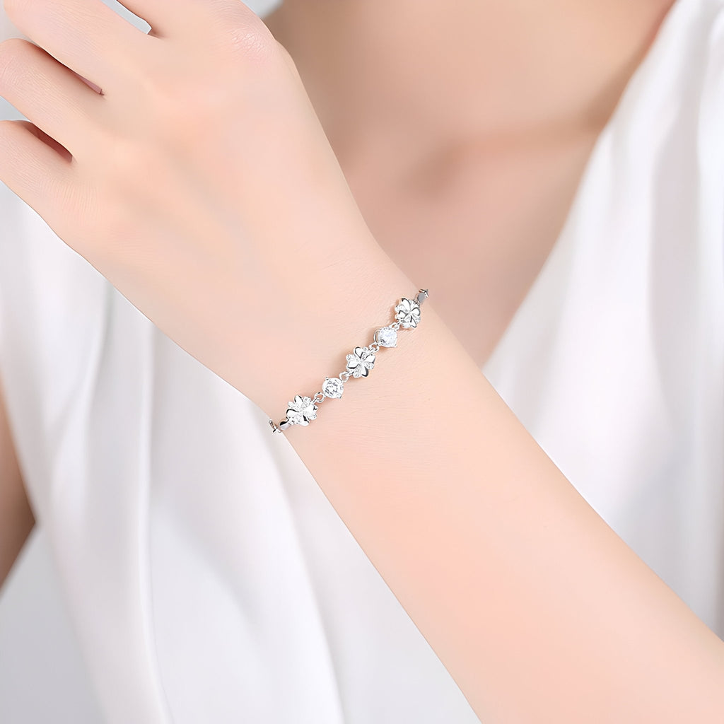 Bracelet en argent avec charms trèfles à quatre feuilles élégants porté sur poignet féminin.