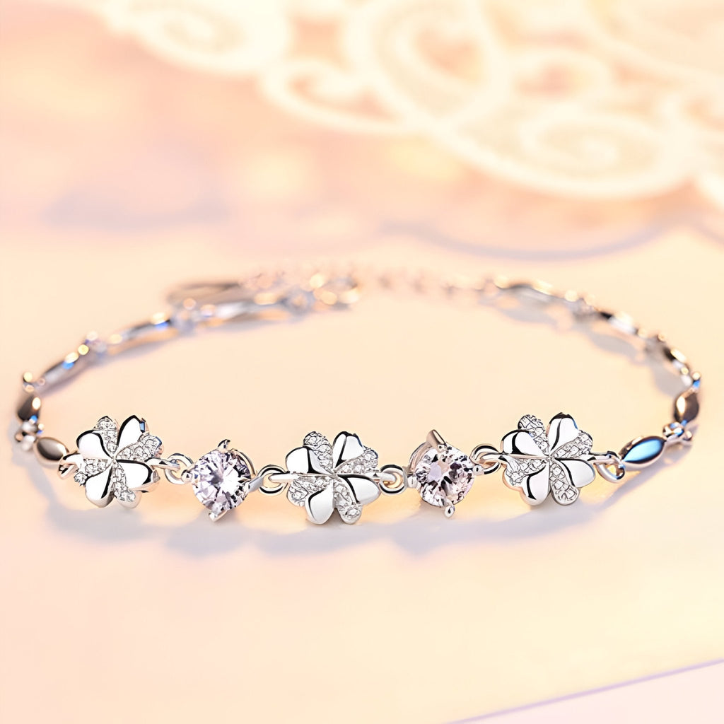 Bracelet en argent avec motifs trèfles à quatre feuilles et zircones scintillantes sur chaîne fine.