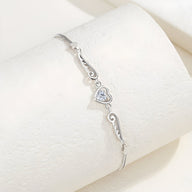 Bracelet en argent sterling avec coeur central serti d'une pierre et ailes d'ange délicates.