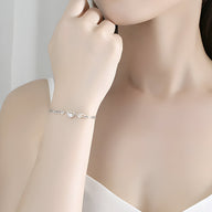 Bracelet en argent sterling avec ailes d'ange et cœur central délicat porté au poignet.