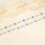 Bracelet fin en argent sterling avec perles bleues et argentées, design ondulé élégant.