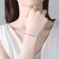 Bracelet en argent sterling fin orné de petites pierres bleues porté au poignet féminin.