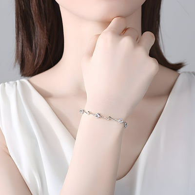 Bracelet en argent sterling fin orné de petites pierres bleues porté au poignet féminin.