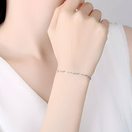 Bracelet fin en argent sterling torsadé porté au poignet féminin sur peau claire, élégant et minimaliste.