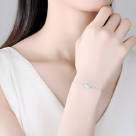 Bracelet fin en argent sterling avec pendentif baleine bleue délicate, porté au poignet féminin.