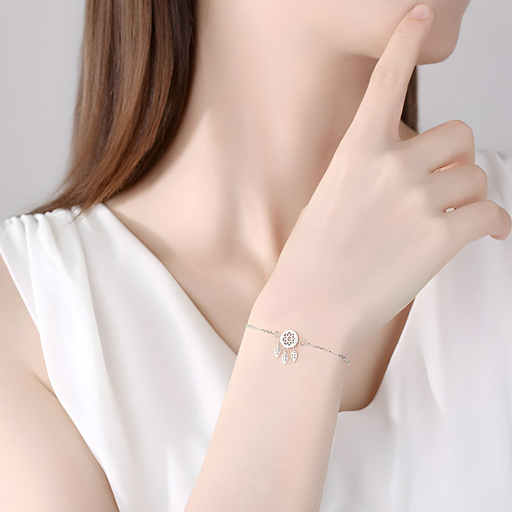 Bracelet fin en argent sterling avec charm attrape-rêves, porté au poignet féminin.