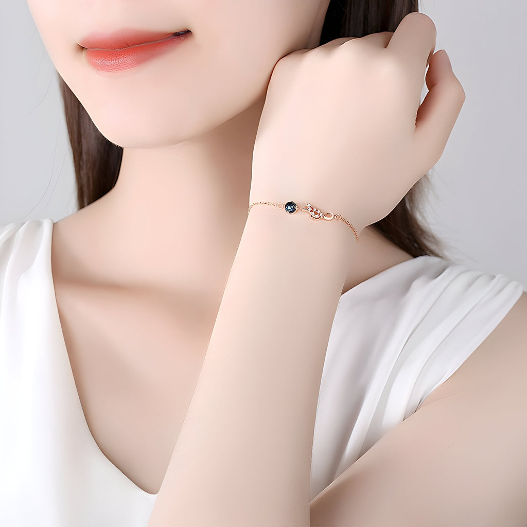 Bracelet fin en argent sterling avec charm chat délicat et petit pendentif noir.