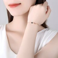 Bracelet fin en argent sterling avec charm chat délicat et petit pendentif noir.