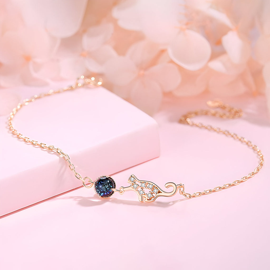 Bracelet en argent sterling avec chaîne fine et charm chat ajouré orné d'une pierre bleue brillante.