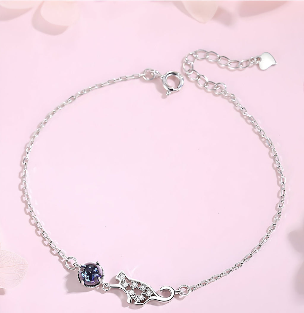 Bracelet fin en argent sterling avec charm chat ajouré et pierre bleue sur chaîne délicate.