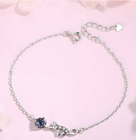 Bracelet fin en argent sterling avec charm chat ajouré et pierre bleue sur chaîne délicate.