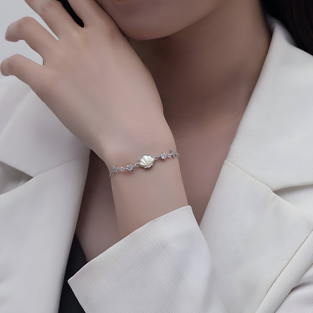 Bracelet en argent sterling avec charme coquillage et étoiles de mer fines, style délicat pour femme.