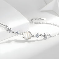 Bracelet en argent sterling avec pendentifs coquillage nacré et étoiles de mer, détails cristaux transparents.
