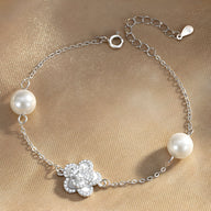 Bracelet en argent sterling avec charm floral orné de cristaux et perles blanches élégantes.