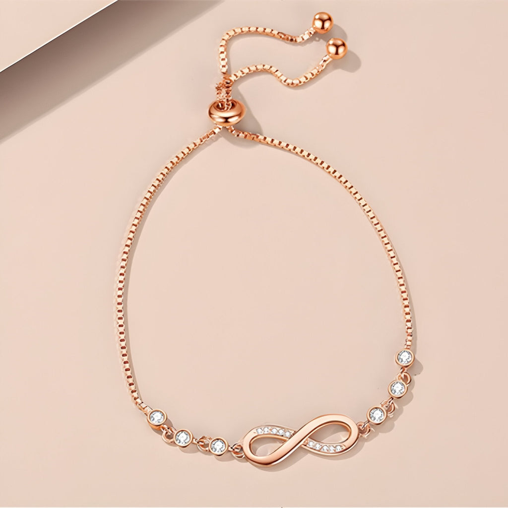 Bracelet en argent rosé avec chaîne ajustable et charm infini orné de petites perles blanches.