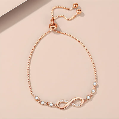 Bracelet en argent rosé avec chaîne ajustable et charm infini orné de petites perles blanches.