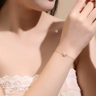 Bracelet fin en argent avec charm papillon délicat porté sur poignet féminin.