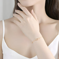 Bracelet fin en argent sterling avec charms géométriques porté au poignet féminin, style minimaliste.