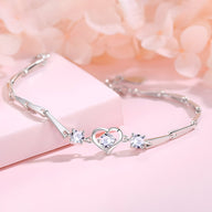 Bracelet en argent sterling avec cœur central ciselé entouré de deux pierres brillantes, style élégant et raffiné.