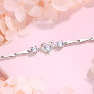 Bracelet en argent sterling avec cœur central ajouré et deux pierres brillantes sur chaîne fine.