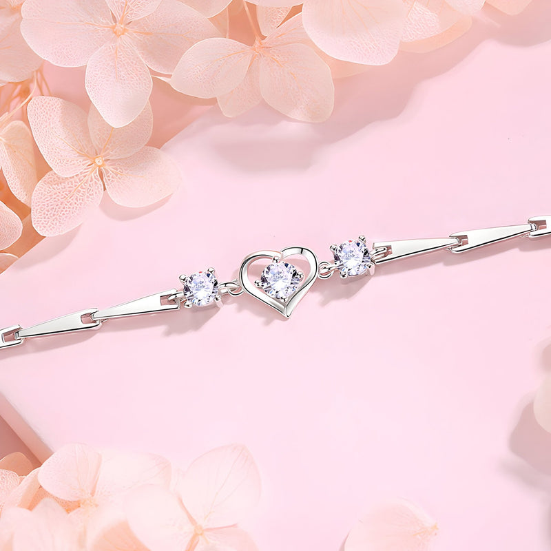 Bracelet en argent sterling avec cœur central ajouré et deux pierres brillantes sur chaîne fine.