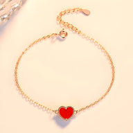 Bracelet fin en or rosé avec petit cœur rouge émaillé, fermoir ajustable.