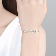Bracelet fin en argent sterling avec petits cœurs irréguliers porté au poignet féminin.