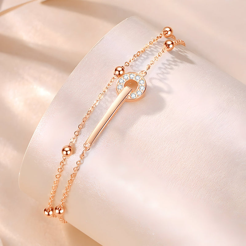 Bracelet en argent rose double chaîne avec barre centrale ornée de petits cristaux blancs.