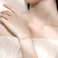 Bracelet fin en argent rose avec design barrette et détail cercle sur peau féminine.